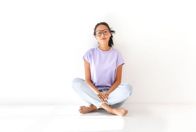 Portrait of a smiling young woman sitting against white background