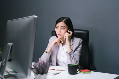 Young woman using mobile phone while sitting on table