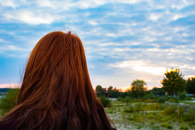 Redhead woman against cloudy sky during sunset