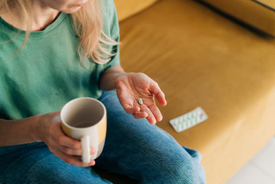 Midsection of woman holding coffee on table