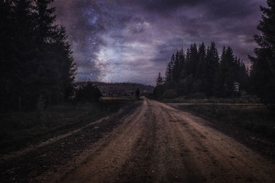 Road amidst trees against sky at night