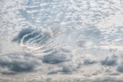 Low angle view of fighter plane in airshow against cloudy sky