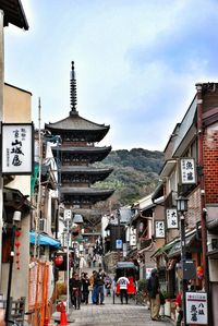 People walking on street by yasaka pagoda against sky