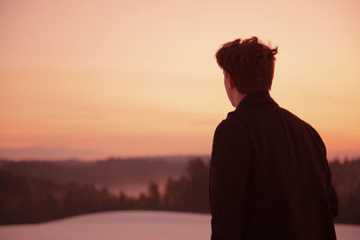 Rear view of silhouette man standing against sky during sunset