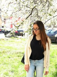 Young woman wearing sunglasses standing against plants