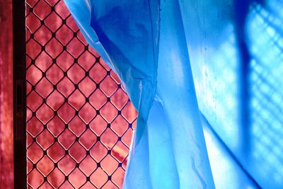 Close-up of metal fence against blue sky