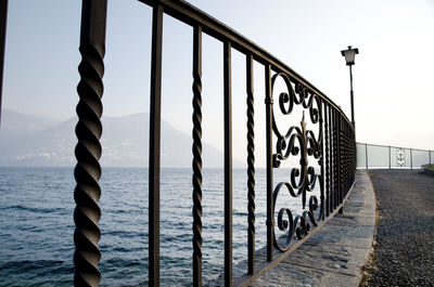 Metal railing by sea against clear sky