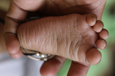 Cropped hand of parent holding baby leg 