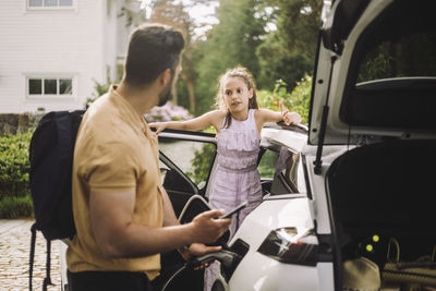 Daughter talking to father charging electric car