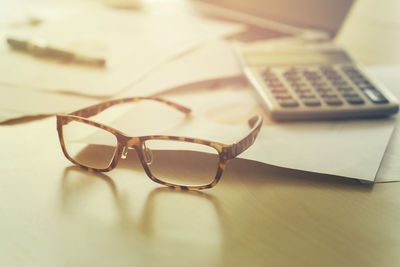 Close-up of eyeglasses with calculator on table