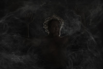 Portrait of shirtless man against black background