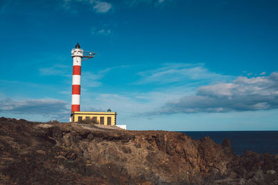 Lighthouse by sea against sky