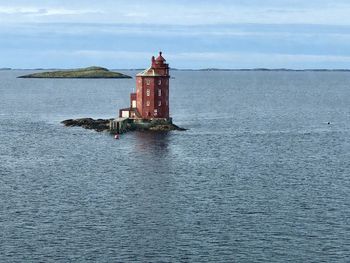 Lighthouse by sea against sky