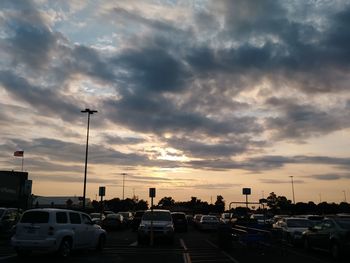 Cars moving on road against cloudy sky