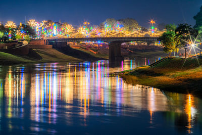 Illuminated bridge over river against sky at night