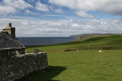 Scenic view of stone house on grass landscape