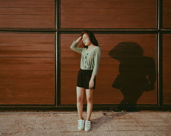 Full length of woman standing against wooden wall