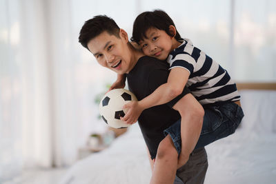 Father and son with soccer ball at home