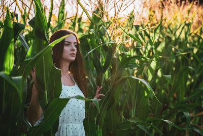 Portrait of young woman standing amidst plants