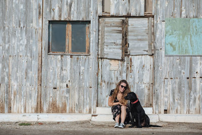 Woman sitting with dog against old house