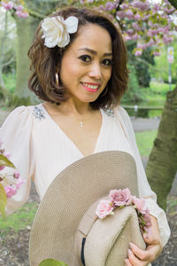 Close-up portrait of happy woman with flowers on tree