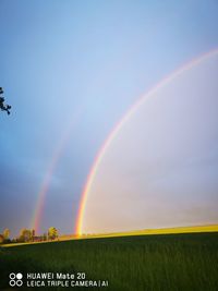Scenic view of rainbow over field against sky