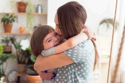 Loving mother embracing boy with down syndrome