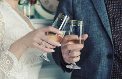 Midsection of wedding couple toasting champagne flutes