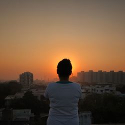 Rear view of man standing on city during sunset