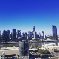 Modern buildings in city against clear blue sky