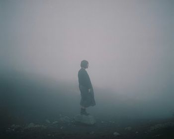 Man standing on landscape in foggy weather