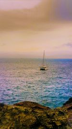 Sailboat sailing on sea against sky during sunset