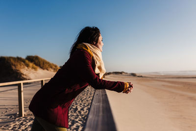 Woman standing on beach against clear sky