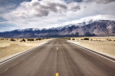 Road by mountains against sky