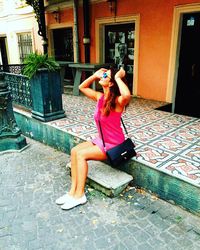 Young woman sitting on wall