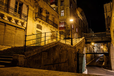 Illuminated street light by building at night