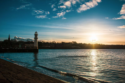 Scenic view of sea and a lighthouse against sky during sunset