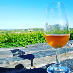 Close-up of beer glass on table against sky