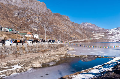 Scenic view of lake and mountains against clear blue sky