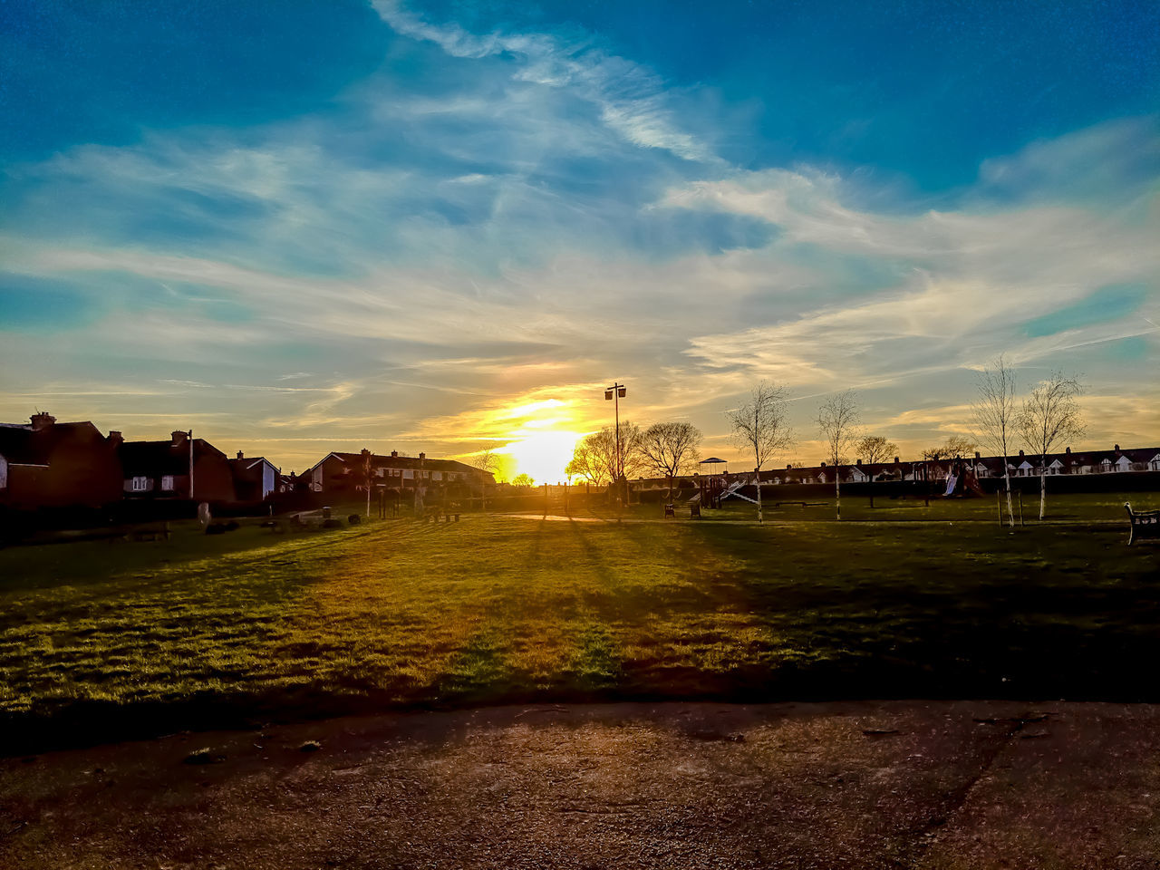 sky, sunset, cloud - sky, nature, sunlight, beauty in nature, field, land, grass, environment, sun, scenics - nature, tranquil scene, architecture, landscape, no people, tranquility, plant, building exterior, built structure, lens flare, outdoors