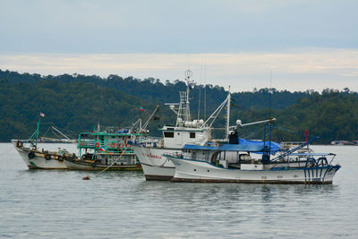 Fishing boats in sea against sky