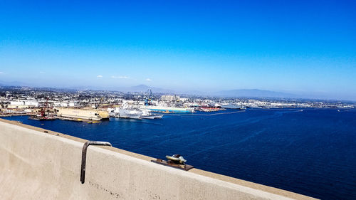 High angle view of sea by cityscape against blue sky