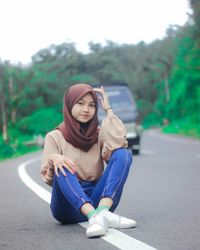 Portrait of smiling young woman sitting on road