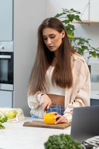 Portrait of young woman using mobile phone while sitting at home