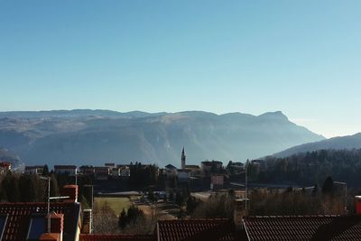 High angle view of houses and mountains against blue sky