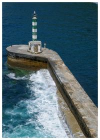 Lighthouse by sea against sky