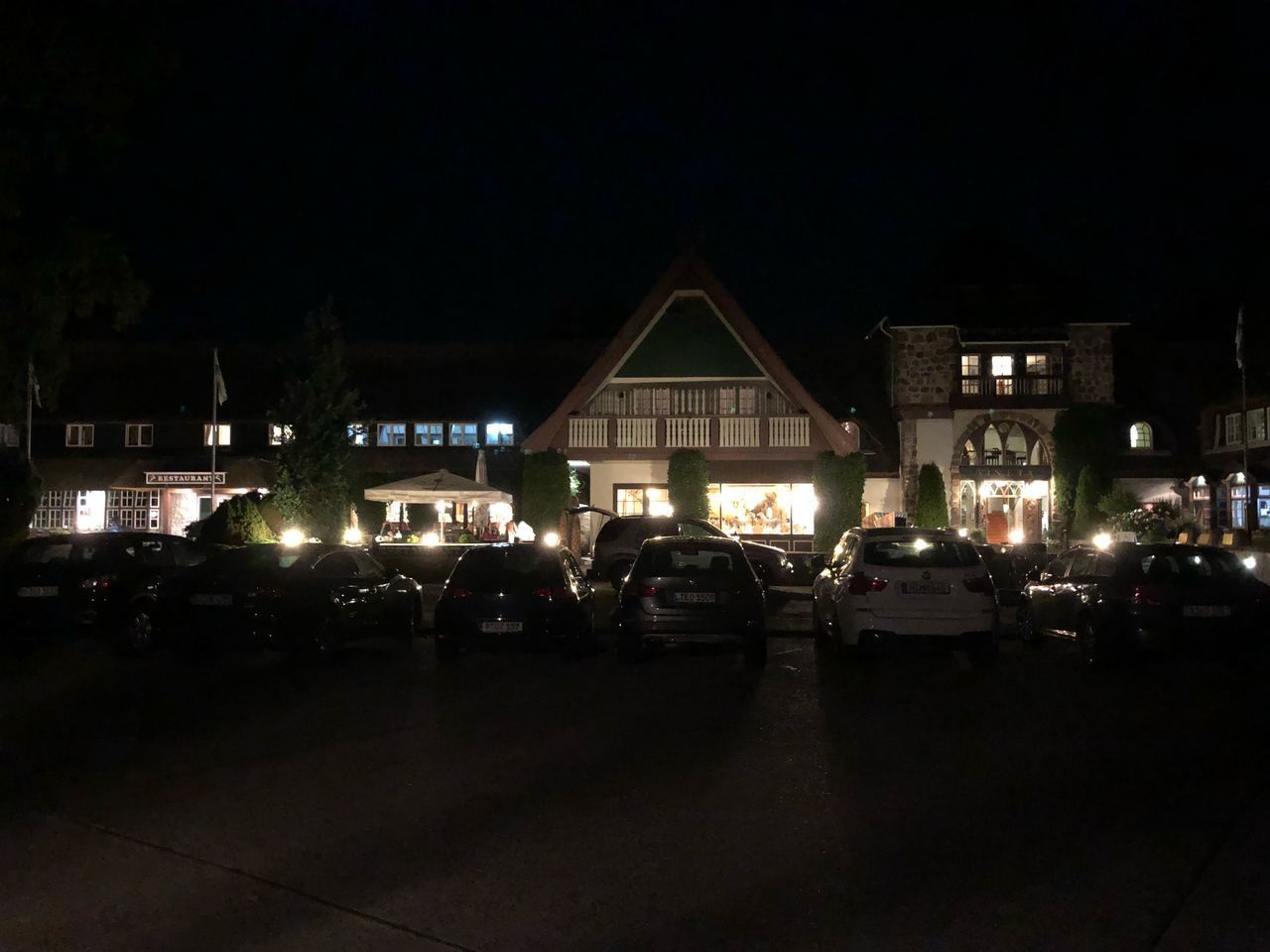 CARS ON ILLUMINATED STREET AMIDST BUILDINGS AT NIGHT