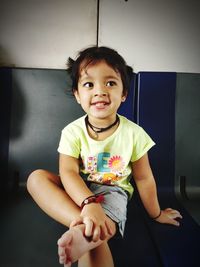 Cute baby girl sitting on chair at home