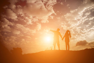 Silhouette friends standing against sky during sunset