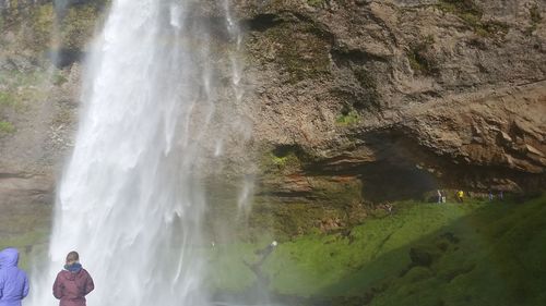 Rear view of two people looking at waterfall